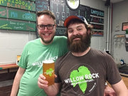 Willow Rock Brewing Company founders standing behind their bar holding a glass of beer.